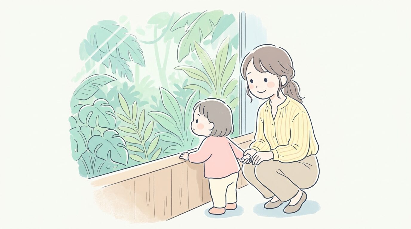 動物科学館の屋内展示で熱帯雨林の緑を背景に興味深そうに見つめる2歳児と母親